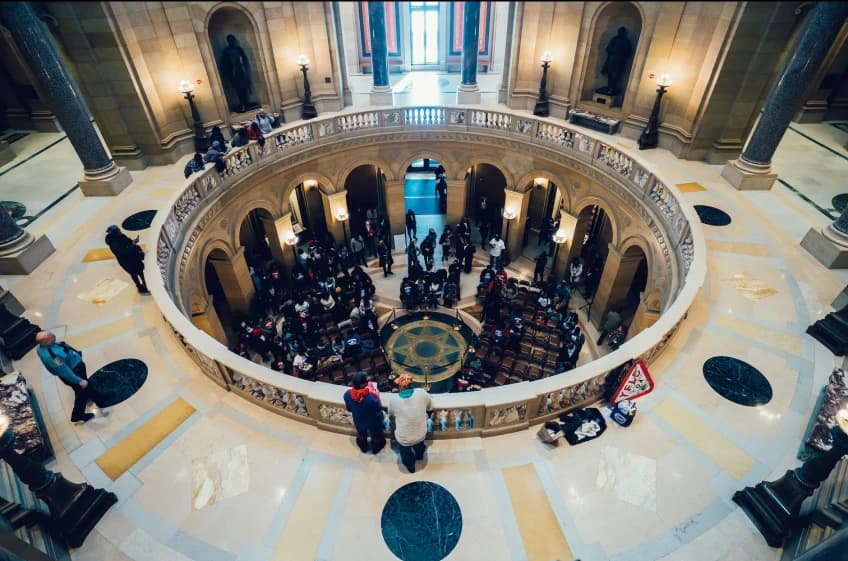 A group of people are standing on a circular floor in a building.